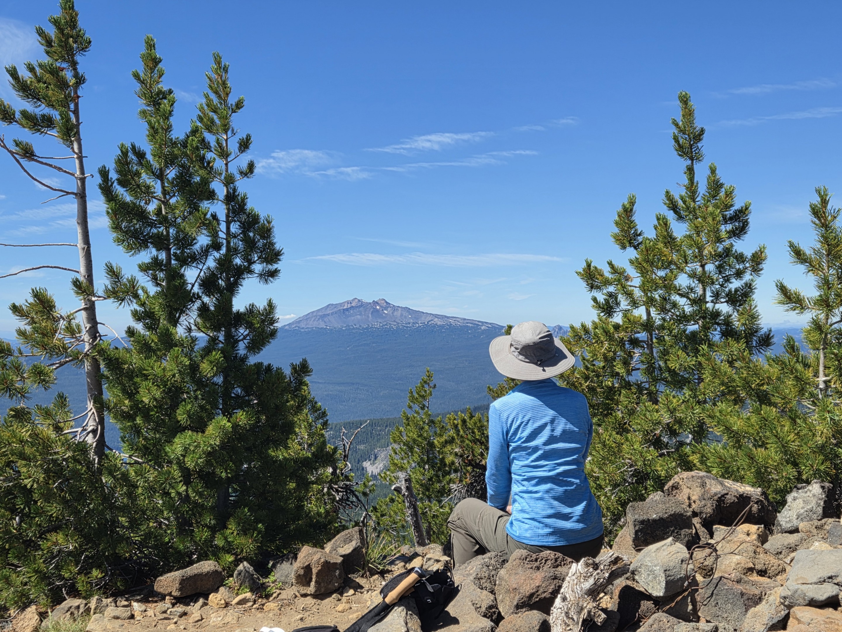 Hiker overlooking Diamond Peak from the summit of Maiden Peak